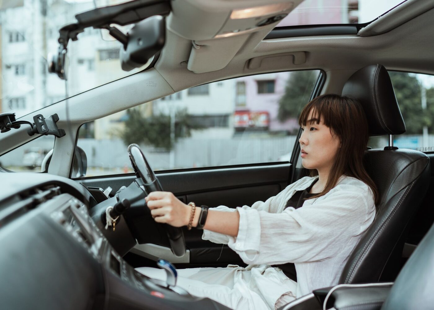 Driver behind the wheel on a city street, reviewing what her car insurance costs
