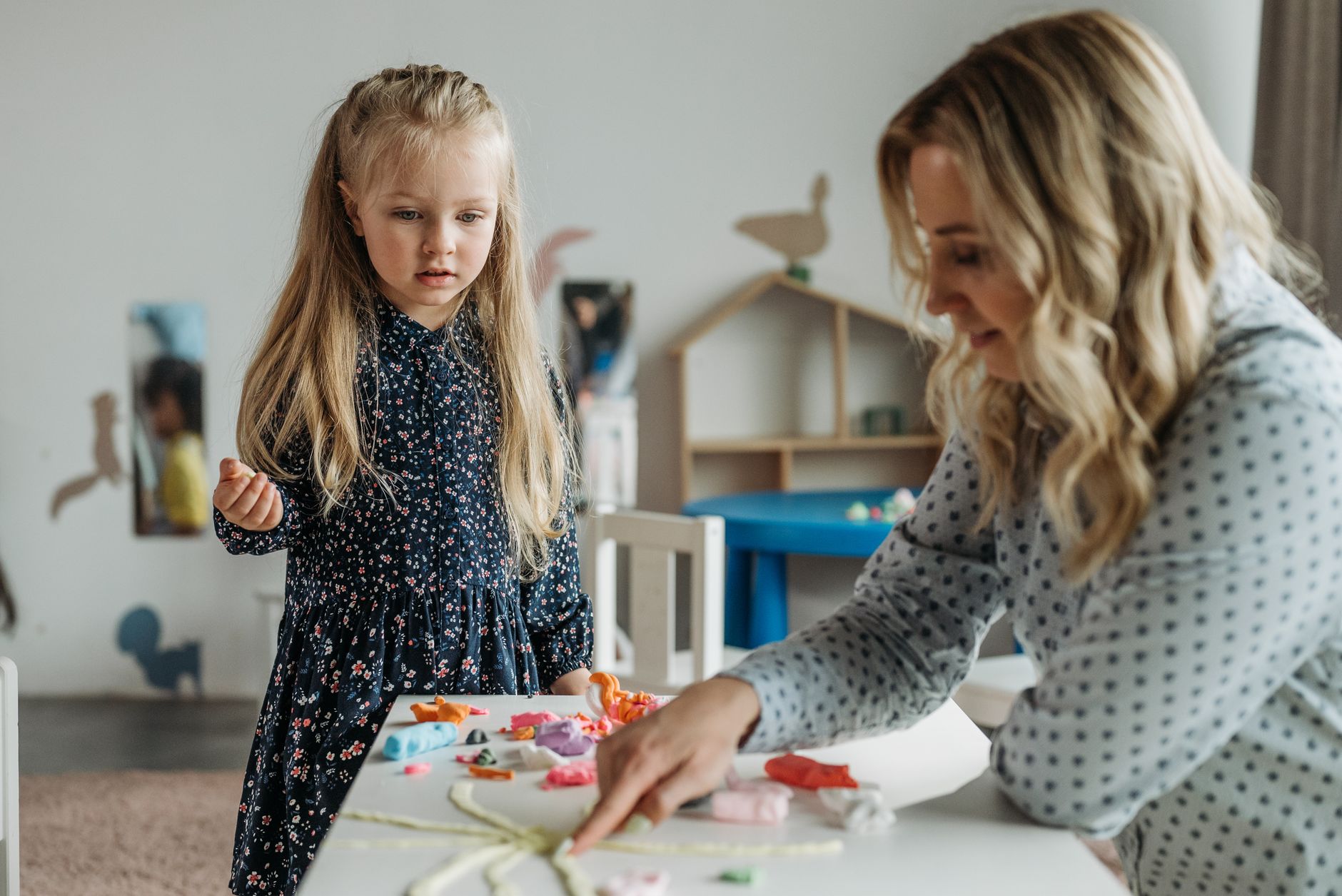 Teacher and young child doing a craft activity in a preschool classroom