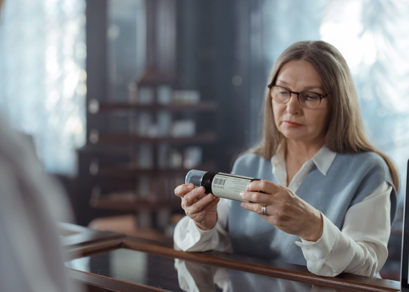 Woman reading a prescription bottle at a pharmacy counter, an FSA-eligible expense