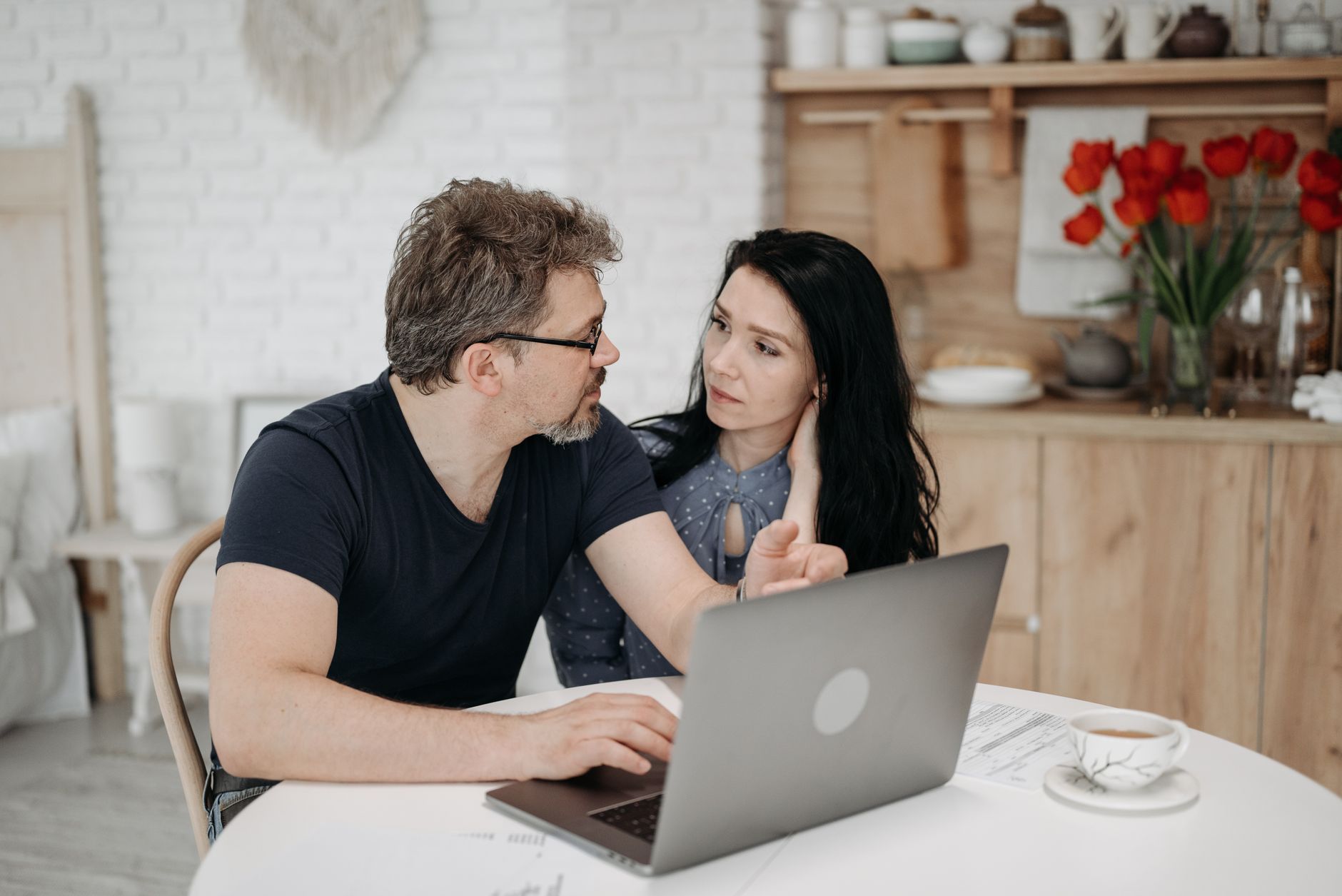 Couple comparing flight and hotel totals on a laptop while planning a family summer trip
