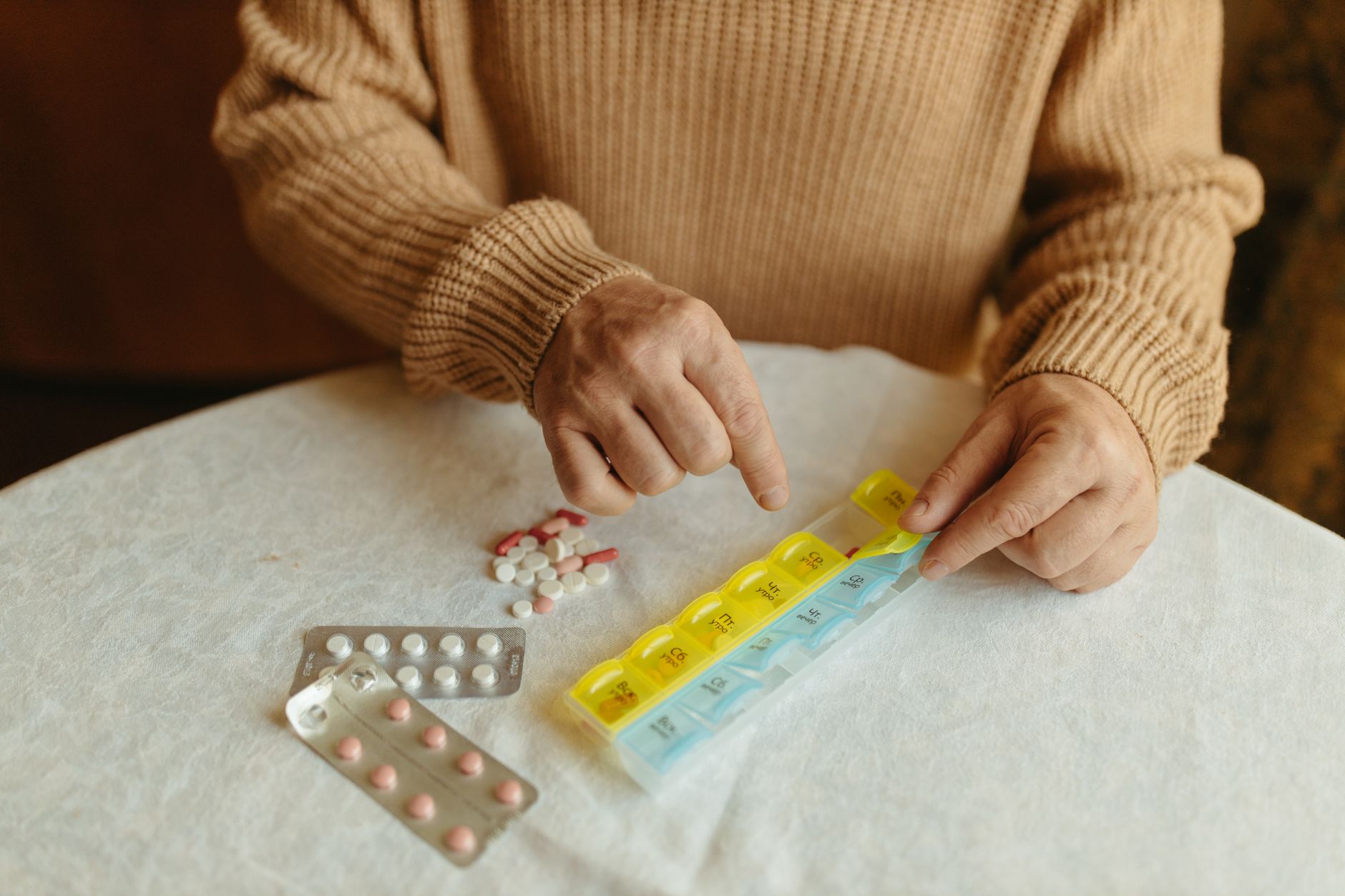 Older adult sorting prescription medications into a weekly pill organizer