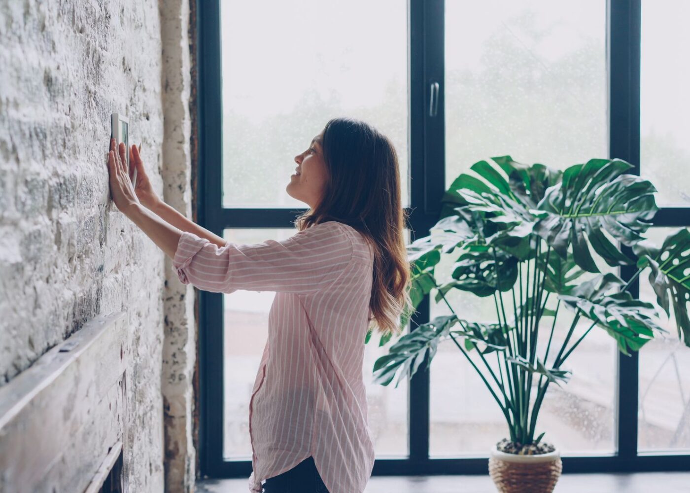 Woman adjusting her home thermostat as heating season approaches