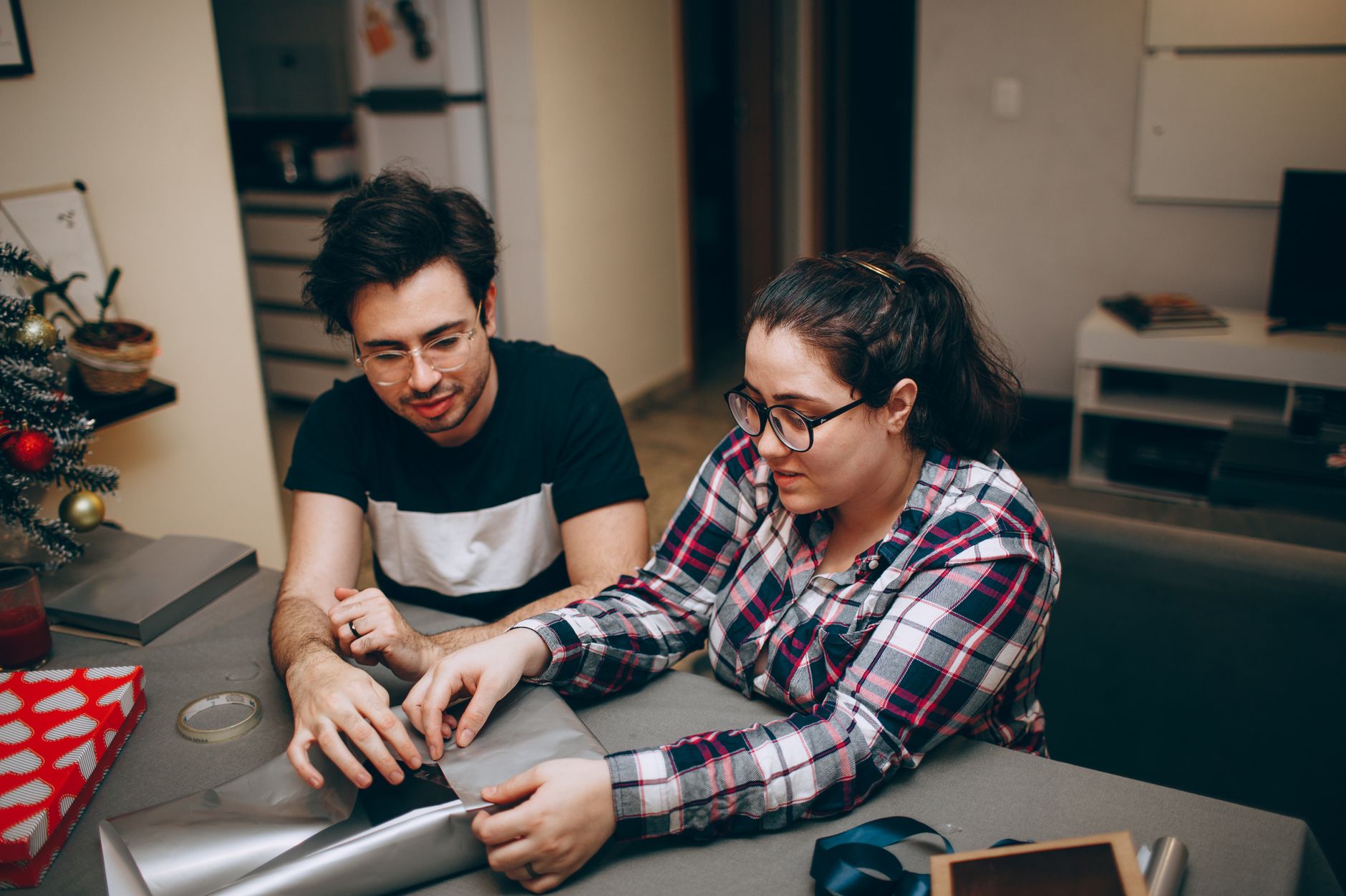 Couple wrapping holiday gifts at home, paid for from a separate holiday savings fund