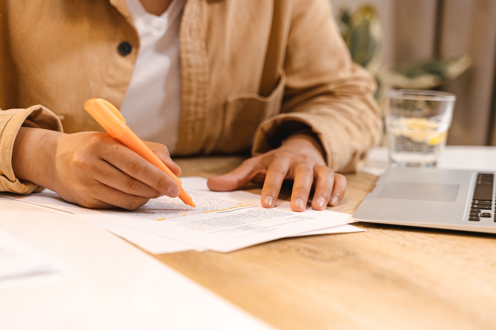Person marking recurring charges on a printed card statement while running a subscription audit