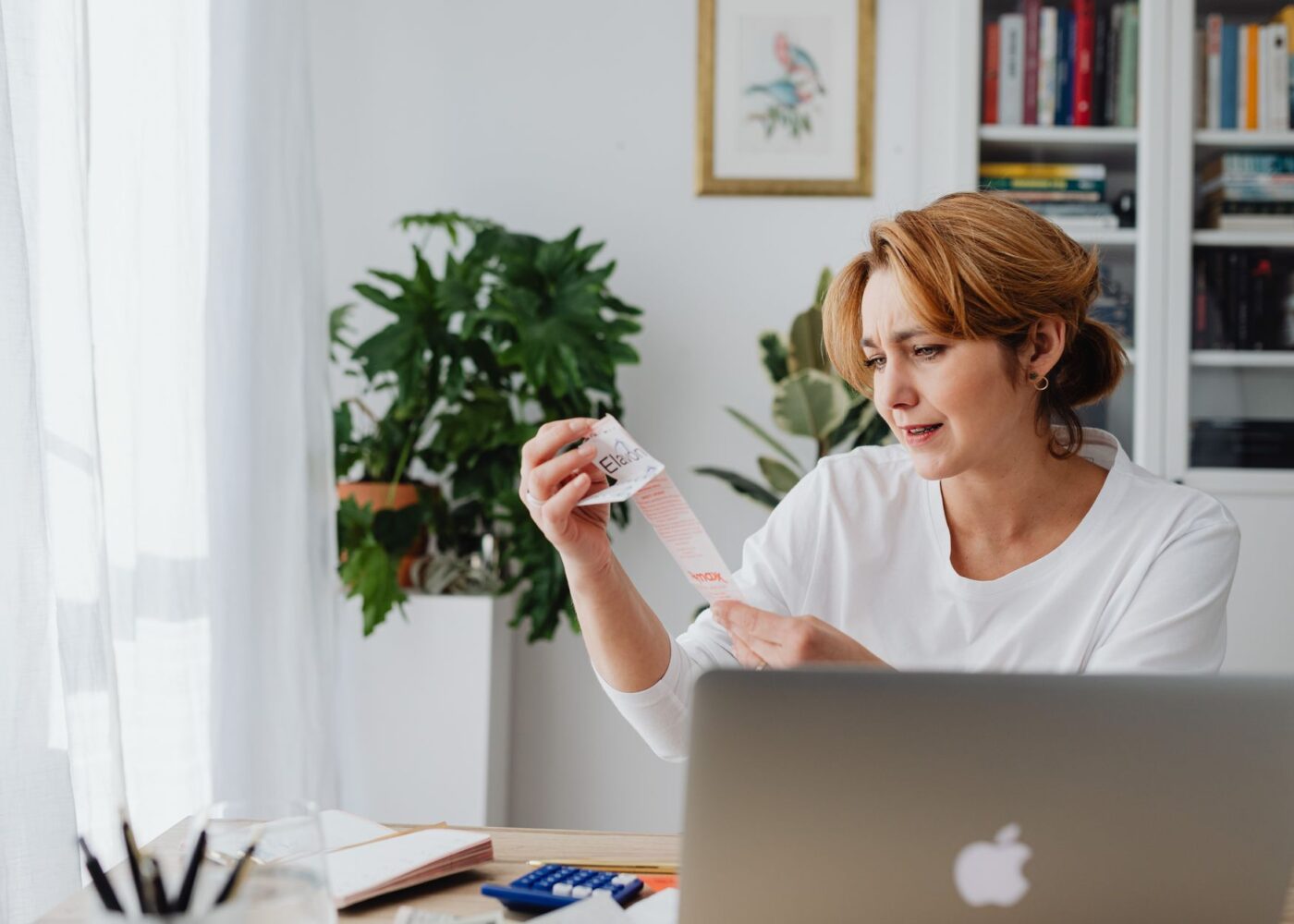 Woman at her kitchen table comparing T-bills vs CDs for her tax refund on a laptop