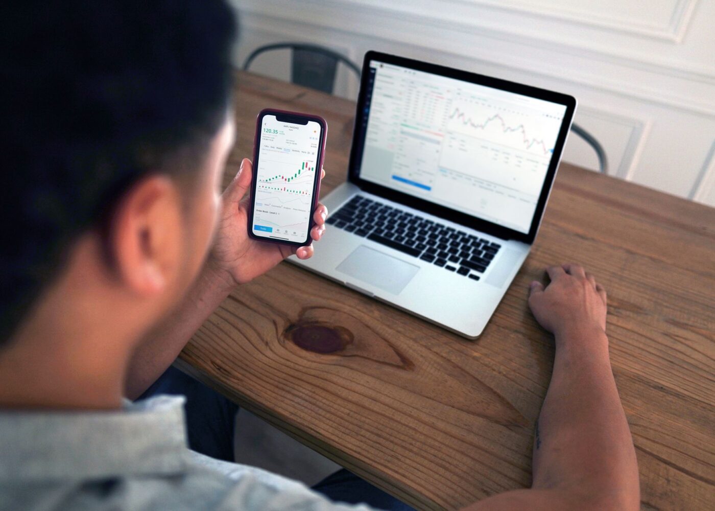 Investor reviewing a losing stock fund position on a laptop and phone at home